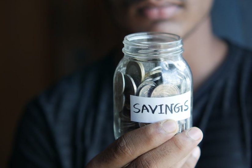 Man holding his savings in a coin jar