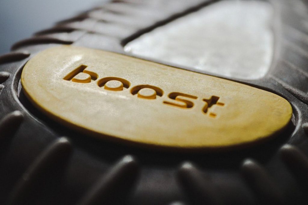A close-up photograph focused on the engraved word “boost” on a wooden surface—evoking the concept of a fiscal “investment boost” introduced in New Zealand’s Budget 2025